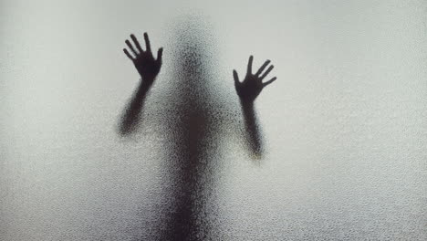 A female silhouette behind the frosted window touches the glass slowly
