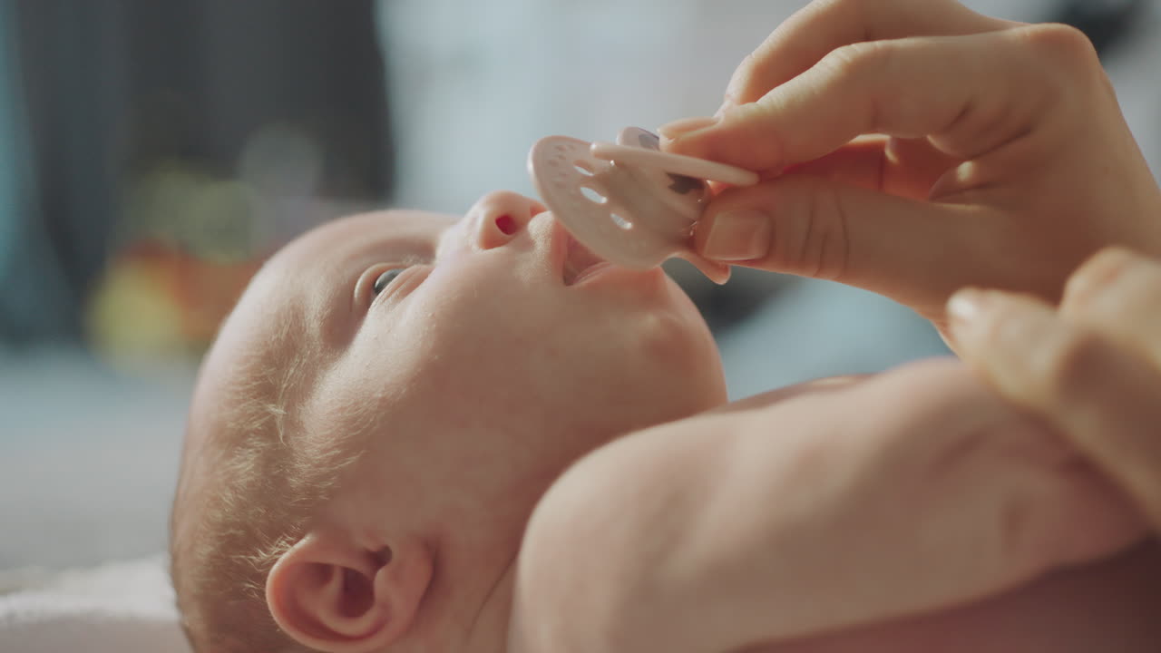 Mother giving pacifier to newborn baby
