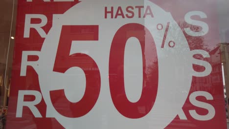 signo de liquidación a mitad de precio en la ventana de la tienda en español escrito, inclinado hacia abajo