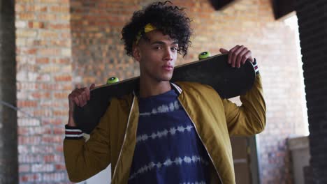 retrato de un hombre afroamericano que lleva una patineta de pie en un garaje vacío