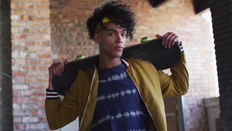 portrait of african american man carrying skateboard standing in empty parking garage