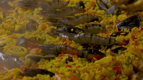 shot of the boiling hot paella pan with tiger shrimps and mussels as ingredients in the saffron rice dish