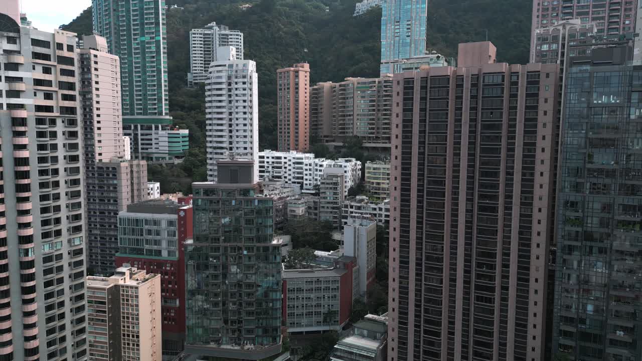 Filmagem aérea panorâmica de drone de edifícios e arranha-céus no centro de Hong Kong em um dia ensolarado, destacando o horizonte denso e a arquitetura urbana moderna