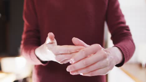 Mid-section-of-woman-sanitizing-her-hands-at-home