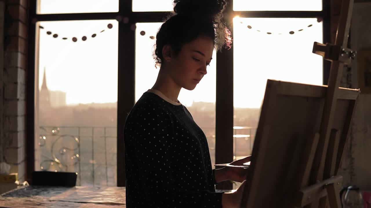 Slow motion footage of a cute female artist in her 20's drawing on easel.