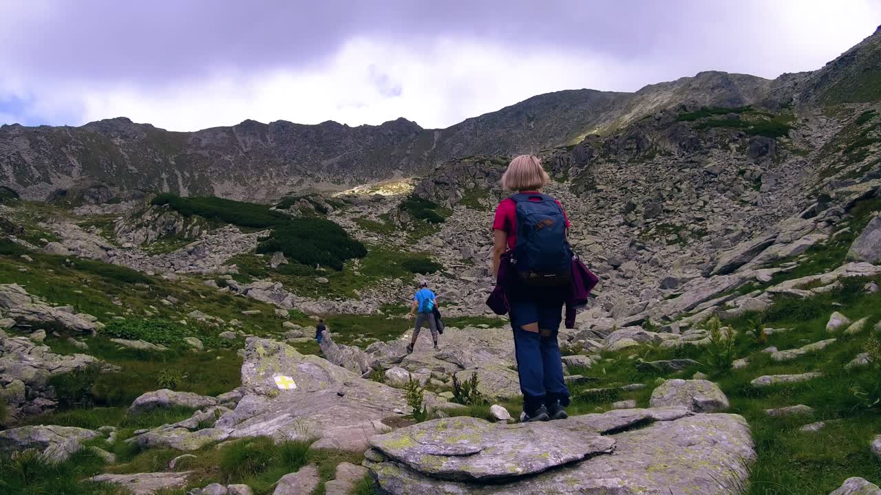 excursionistas caminando por la ladera de una montaña en la ladera rocosa de rumania