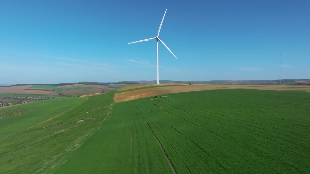 풍력 터빈은 은 파란 하늘 아래 광활한 초록색 에 높이 서 있습니다.
