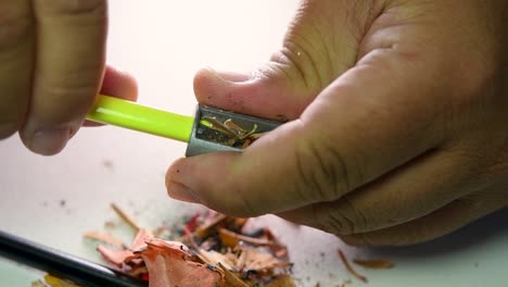 images de mains affûtant lentement un crayon et des crayons de couleur avec un taille-crayon en coin