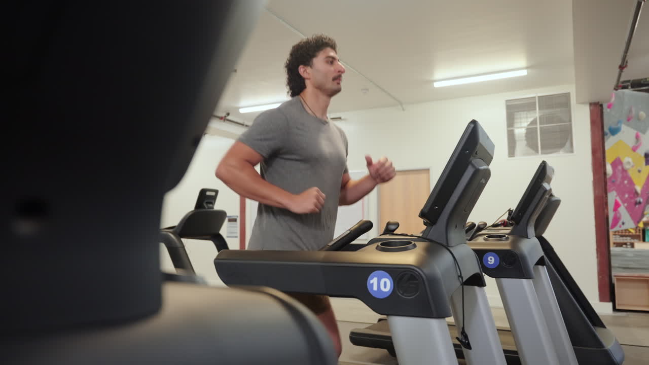 Active Man Running On The Treadmill Of Fitness Club. - wide shot