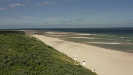 Toma-Aérea-De-Una-Playa-Vacía-Y-Dunas-Verdes-En-La-Reserva-Natural-De-Oranjezon-En-Zelanda,-Los-Países-Bajos,-En-Una-Hermosa-Mañana-Soleada