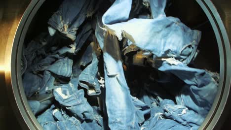 slow motion shot of blue jeans spinning inside an industrial washer dryer in jeans factory