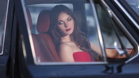 woman in a red dress driving a vintage car