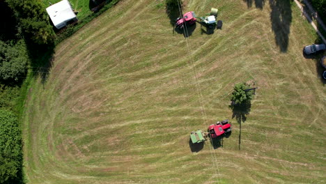 Mehrere-Traktoren-Sammeln-An-Sonnigen-Tagen-Strohballen-Auf-Der-Grünen-Wiese