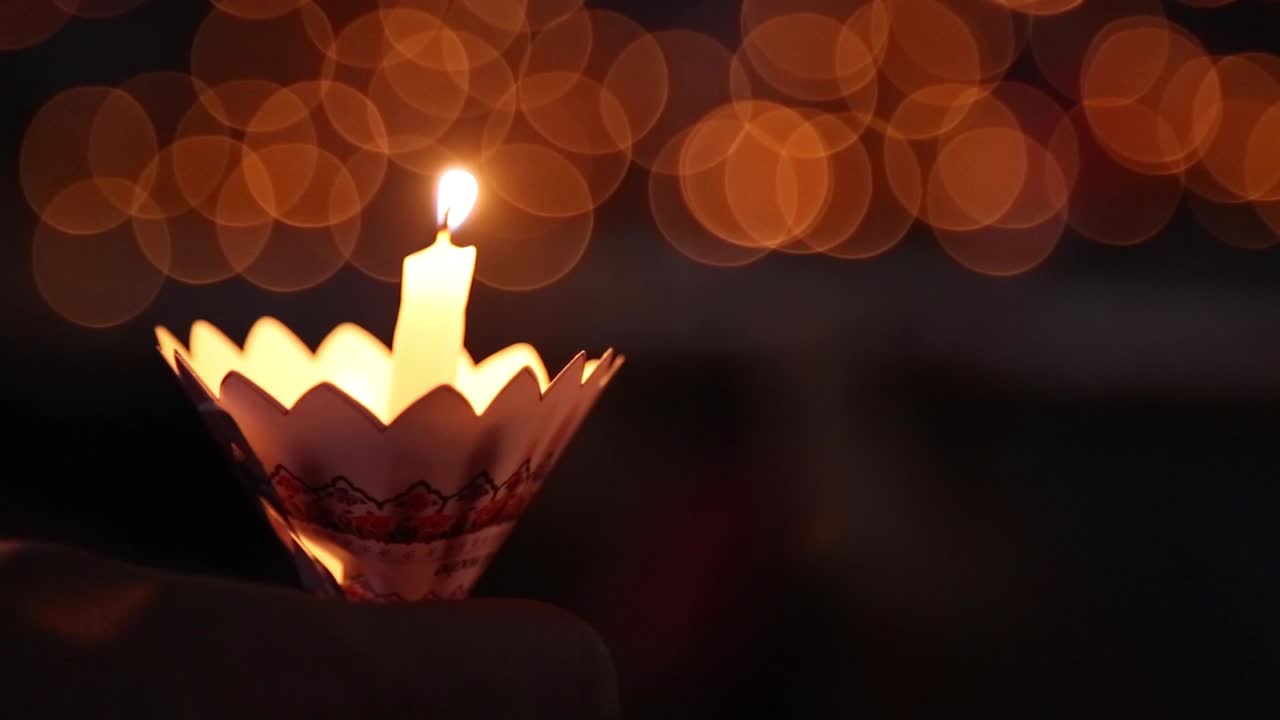Small burning candle being hold during a ceremony with blurry background