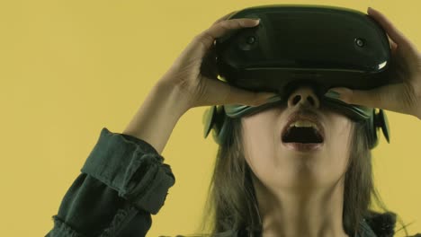 young woman looks around and wonders how amazing  in the vr world. virtual reality helmet on the yellow background. portrait