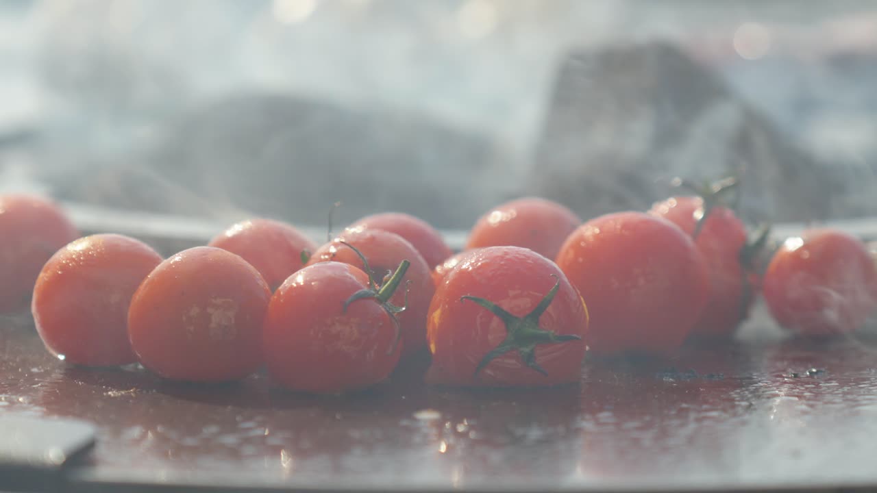 slowmotion close-up of cherry tomatoes on a vine cooking on a bbq