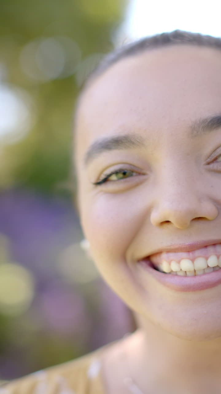 Vertical video: Enjoying sunny day outdoors, smiling woman with natural background