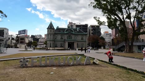 Fukuoka,-Japan--An-old-building-in-Fukuoka,-called-“Kihinkan-Hall”-with-christmas-decoration-and-the-city-sign-"fukuoka"-in-front-of-it