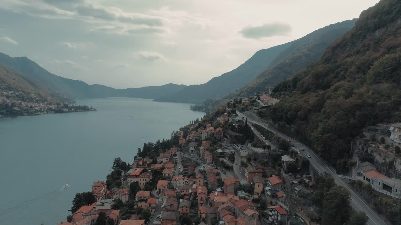 hermosa antena de volar lentamente a lo largo de la costa del lago como en torriggia mostrando casas, caminos, montañas alpinas - cinemática cambiante