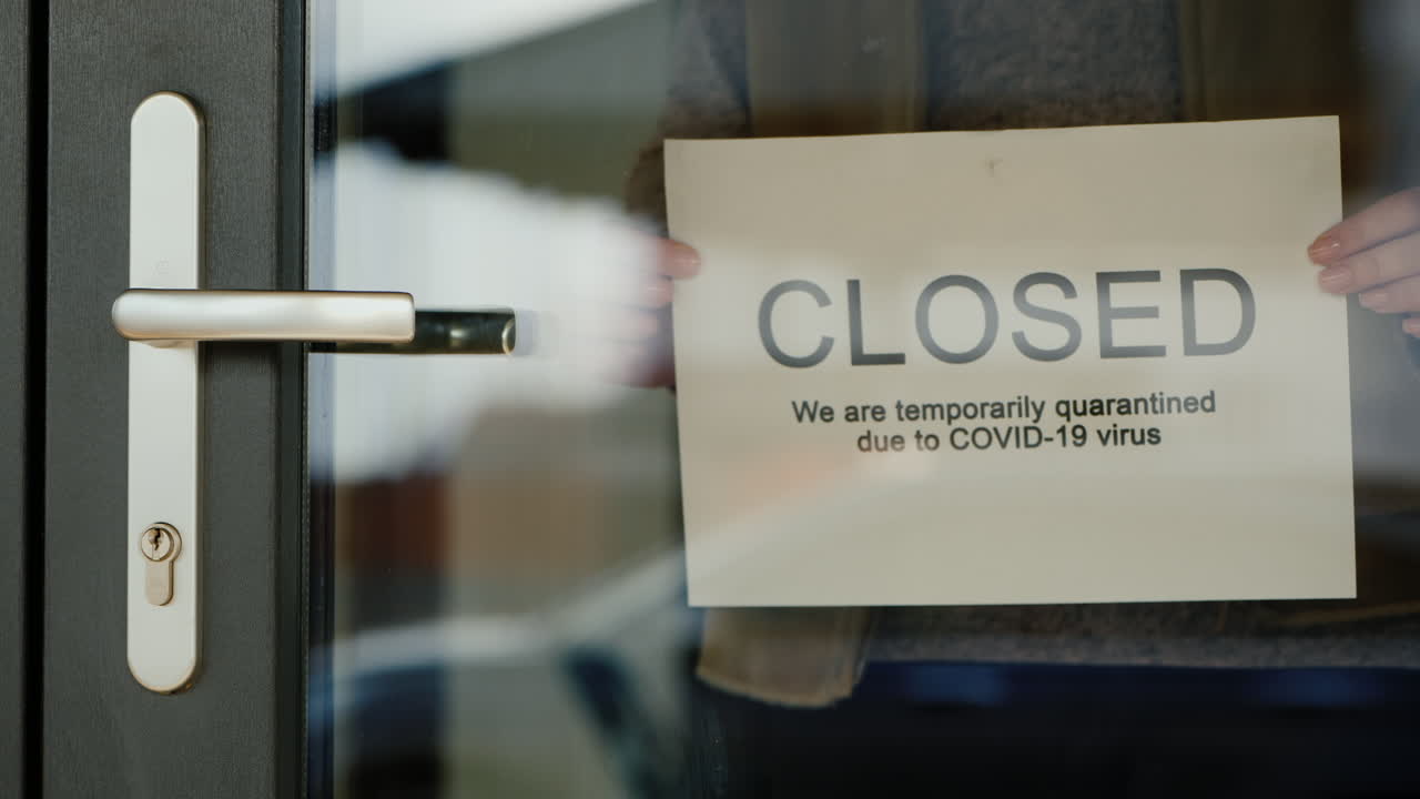 el dueño del negocio cuelga el anuncio de cierre de la puerta debido a la cuarentena del coronavirus