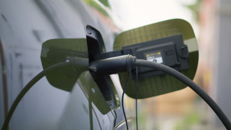 closeup of electric car charging port cover opened to recharge depleted battery,