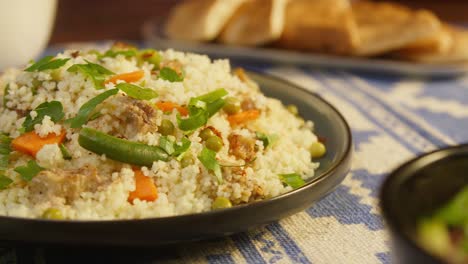 sprinkling greenery on couscous with chicken on table close-up. arabian cuisine. pita and bulgur on background. traditional middle eastern culture. delicious rice with meat. homemade food concept