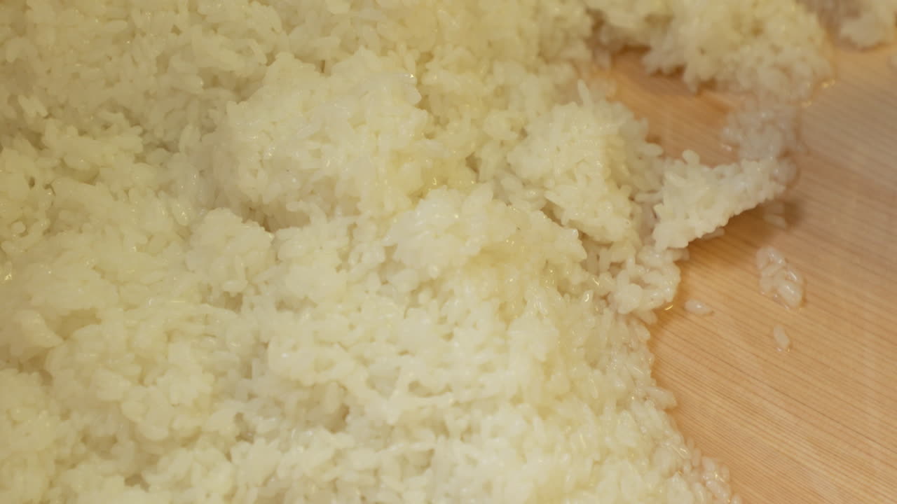 mezclar arroz blanco japonés humedecido con una mezcla de vinagre en el lavabo de madera de la cocina.