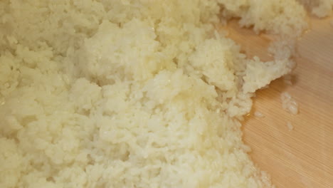 Mixing-Japanese-White-Rice-Moistened-With-Vinegar-Mixture-Into-The-Wooden-Basin-In-The-Kitchen