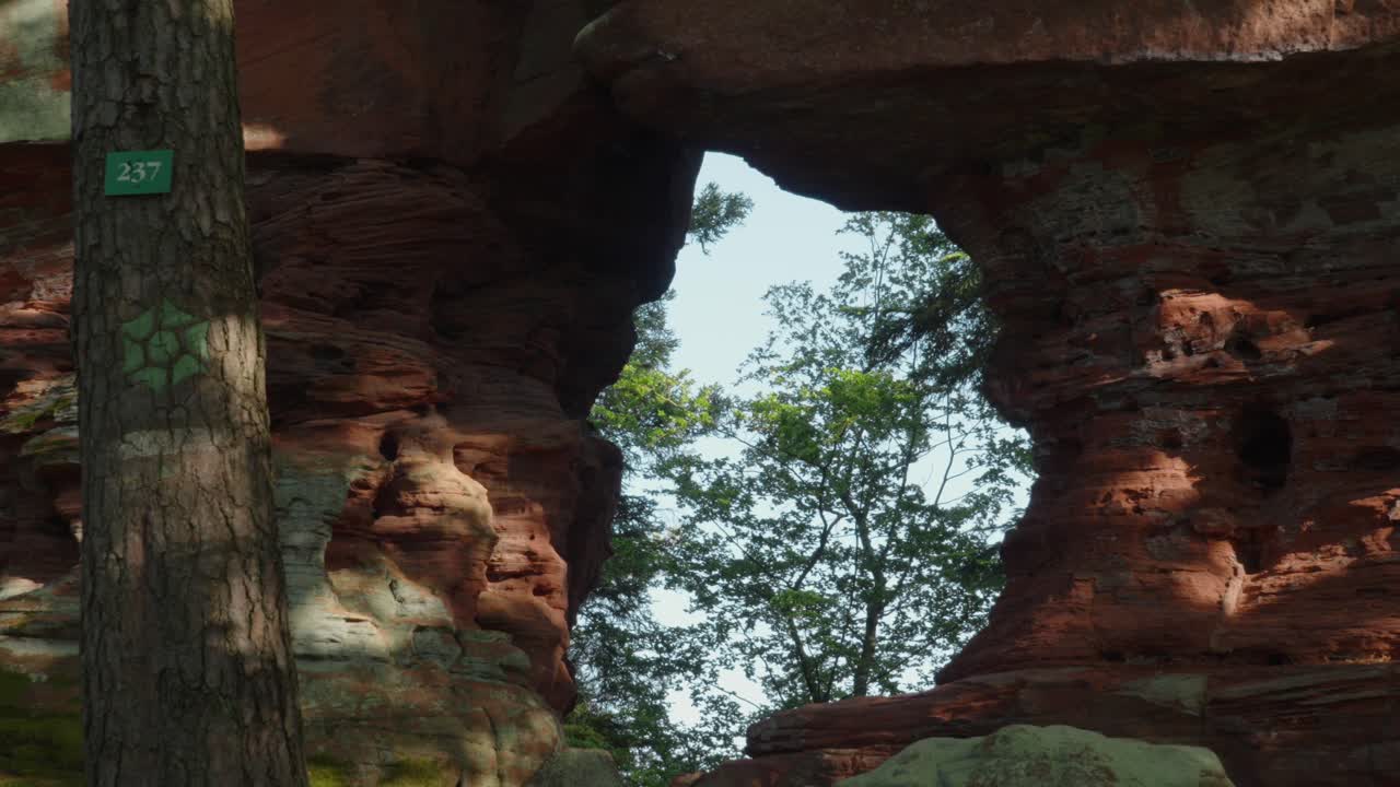 Gap opening in a unique rock formation revealing a forest landscape behind
