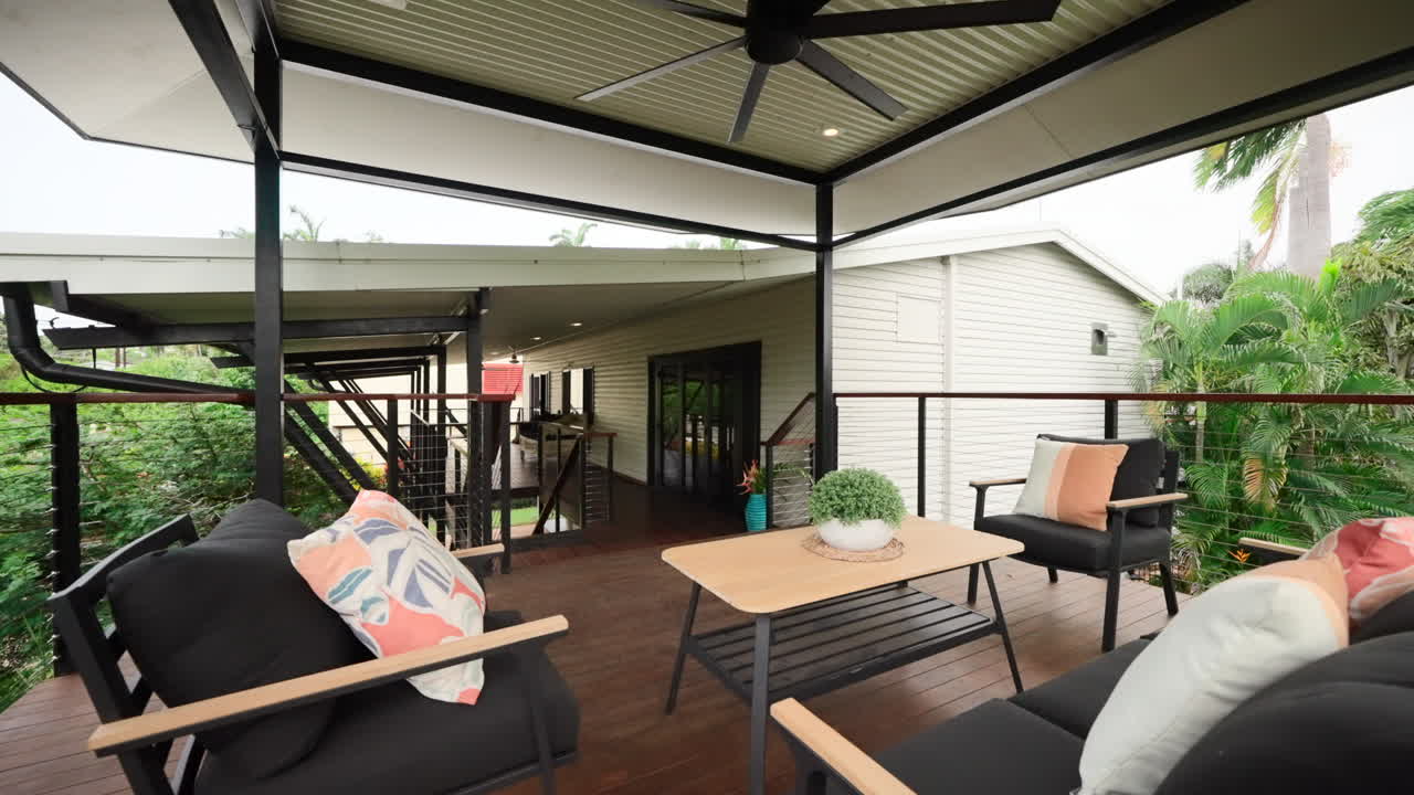 Large Elevated Property House Verandah With Ceiling Fan and Black Beige Patio Furniture. Exterior of home for real estate property.