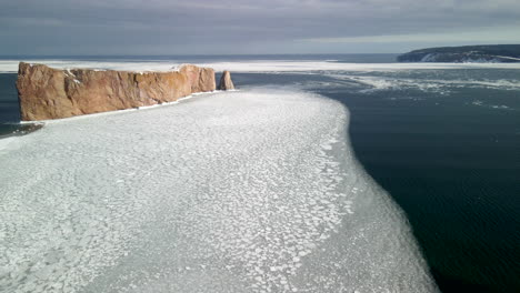 aerial view of percé rock in the winter with ice on the ocean