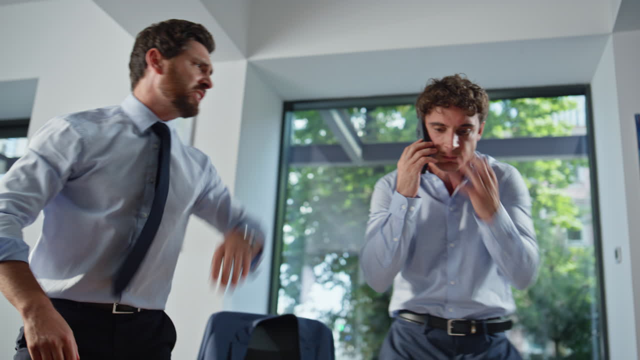 Due startupper nervosi che discutono, vista dal basso di un mobile. Un uomo infuriato telefona con il cellulare