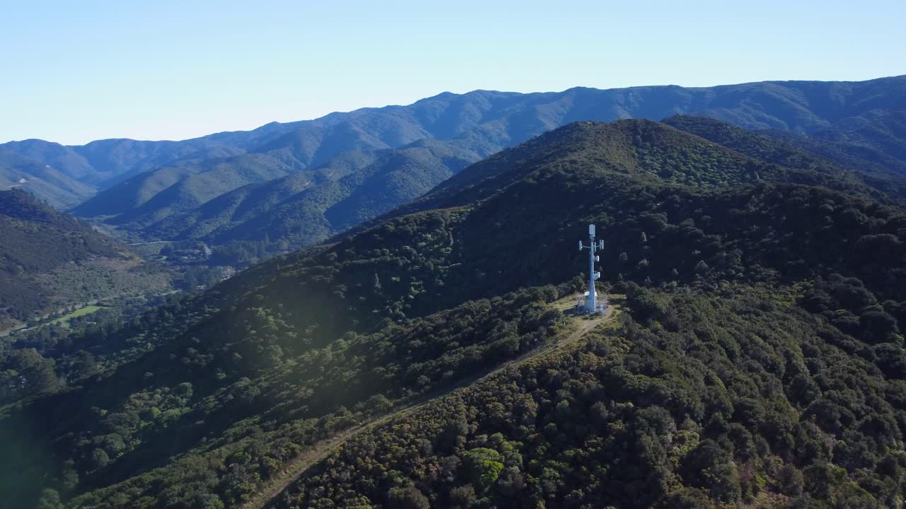 orbitando alrededor de una torre de red en una colina con montañas en el fondo