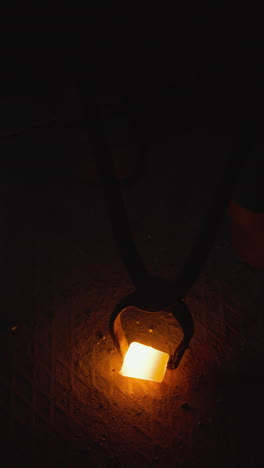 una sola pieza de metal fundido brillante que se maneja en un taller de fundición oscuro