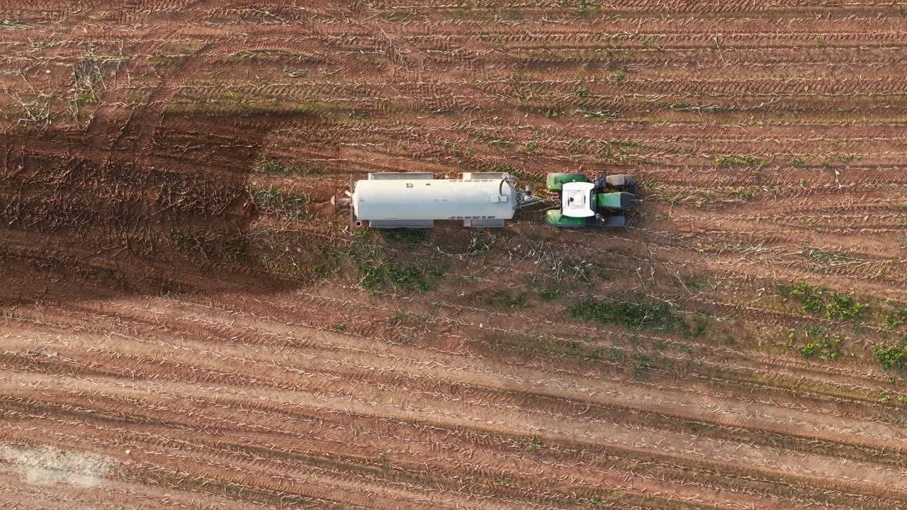 Aerial view of tractor spraying manure on farm field in daylight