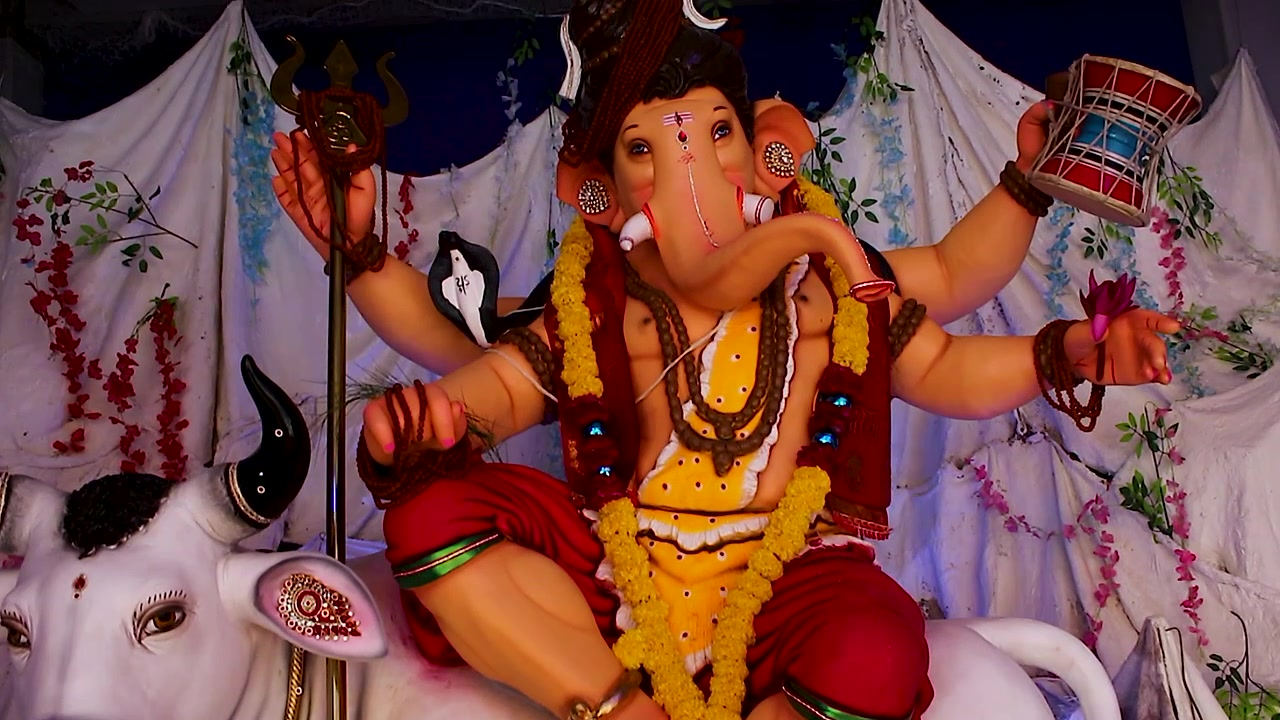 Idolo di Ganesh vestito come il Signore Shiva che tiene un trishul e un damru con movimento jib shot, ghirlande di calendula decorano il pandal durante il festival di Ganesh Chaturthi in India