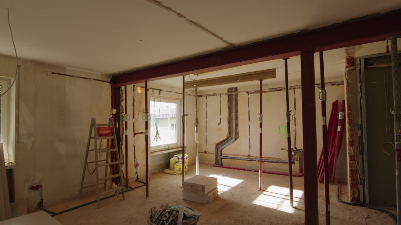 Ampia inquadratura di un cantiere edile, molti pilastri nella stanza che sostengono il soffitto, nuova trave d'acciaio installata