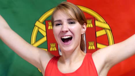 portuguese young woman celebrating while holding the flag of portugal in slow motion