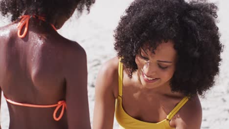 madre afroamericana secando a su hija con una toalla en la playa