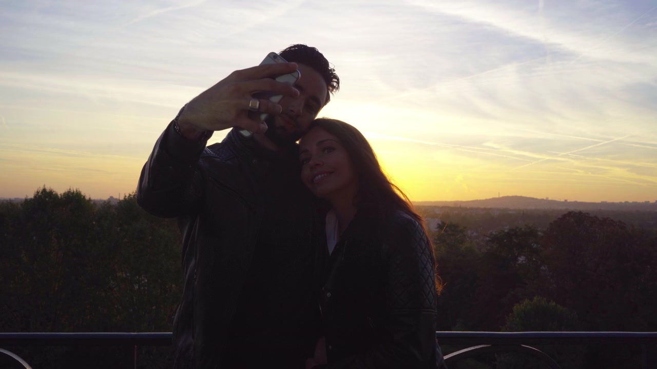 Silhueta de jovem casal tirando selfies na França - sunrinse