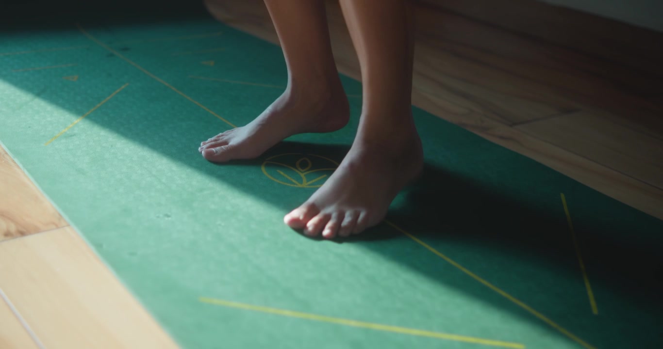 Donna esegue un esercizio di salto a piedi nudi su un tappetino da yoga con luce naturale.
