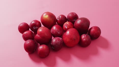 Video-of-fresh-plums-lying-on-pink-surface