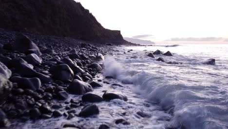 Drohne-Fliegt-Tief-über-Vulkanstrand,-Wellen-Rollen-Auf-Schwarze-Strandkiesel,-Insel-Madeira