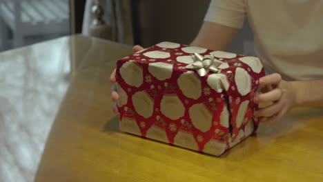 static shot of a man showing off a present wrapped ready for christmas day