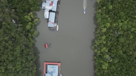 vertical flyover of tourism buildings on tropical river in malaysia