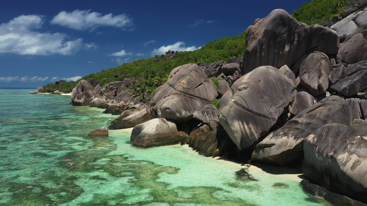 hombre remando en kayak a lo largo de la isla de la digue en las seychelles
