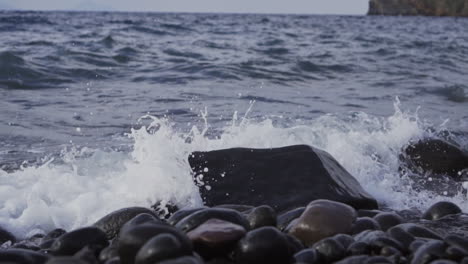 waves hitting rocky beach in slow motion on cloudy day