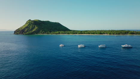 tropical island with surrounding calm sea and tour boats cruising nearby