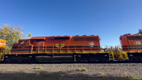 un tren de carga naranja y negro pasa por algunas vías