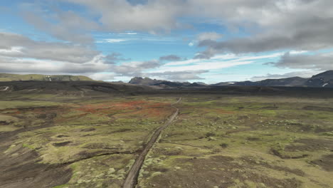 Dirt-road-in-landscape-with-mountains-and-clouds-aerial-Iceland